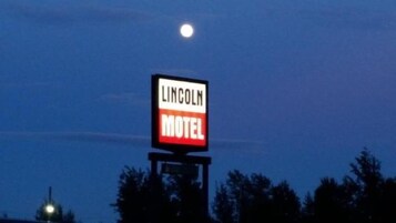 Un letrero de motel con el nombre 'Lincoln Motel' sobre un cielo nocturno con luna visible.