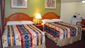 Une chambre d’hôtel avec deux lits, une table de chevet avec une lampe et un micro-ondes posé sur une petite table.