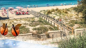 Una playa con sombrillas, sillas y una valla de madera.