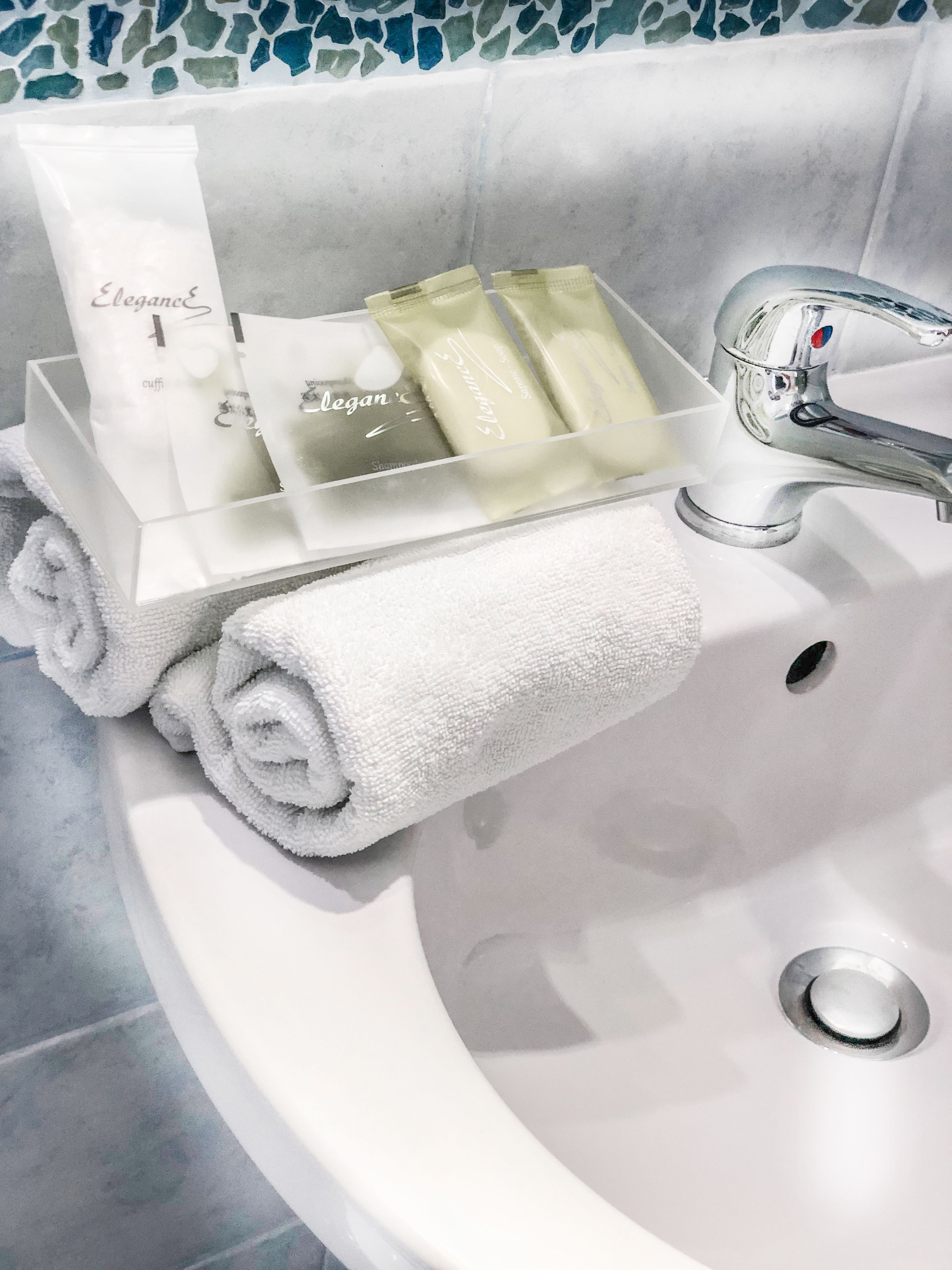 Ein Waschtisch mit Pflegeprodukten, einem Handtuch und einem Wasserhahn.