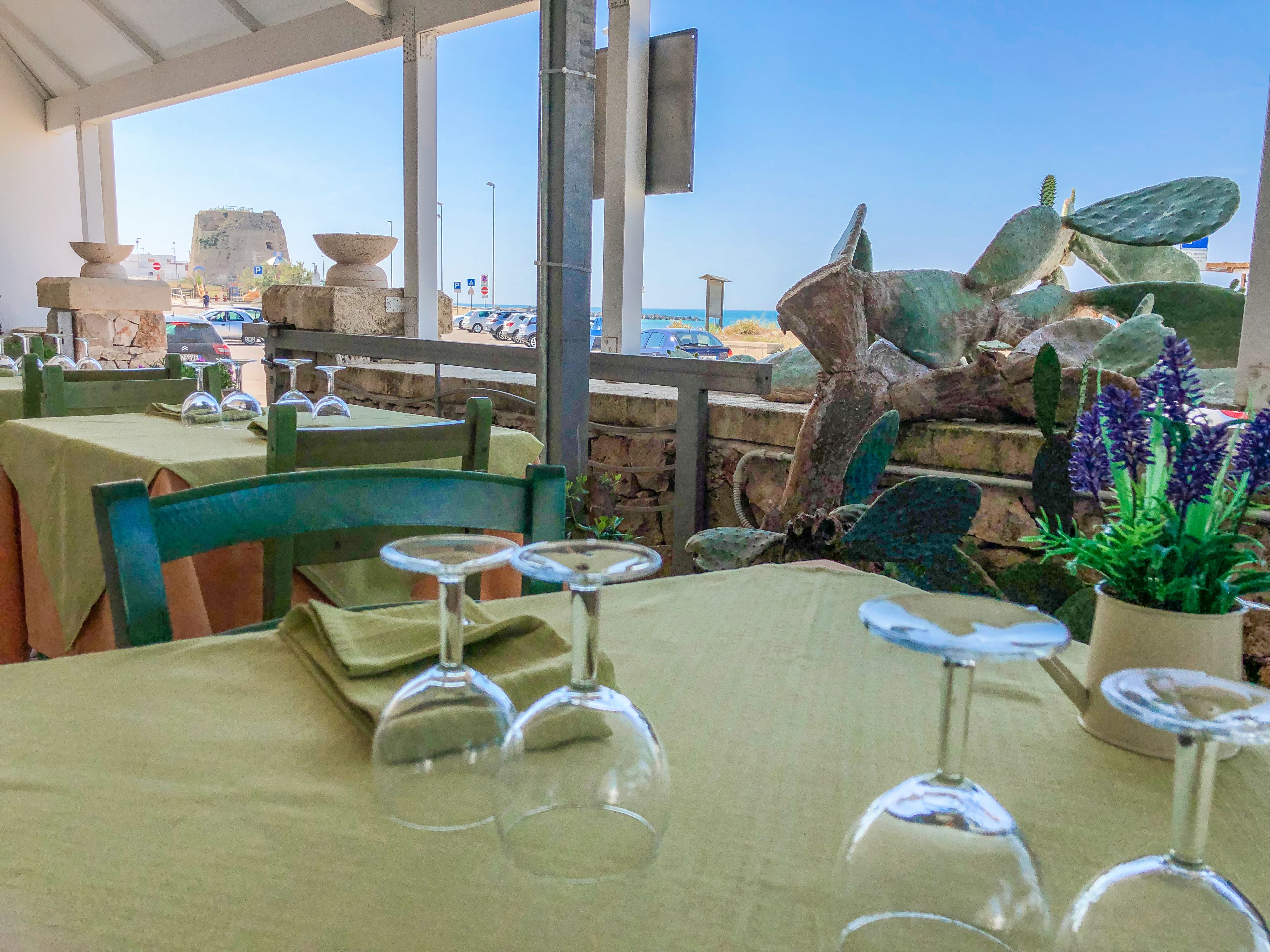 Un área de comedor al aire libre con mesas dispuestas para dos, con vista al mar.