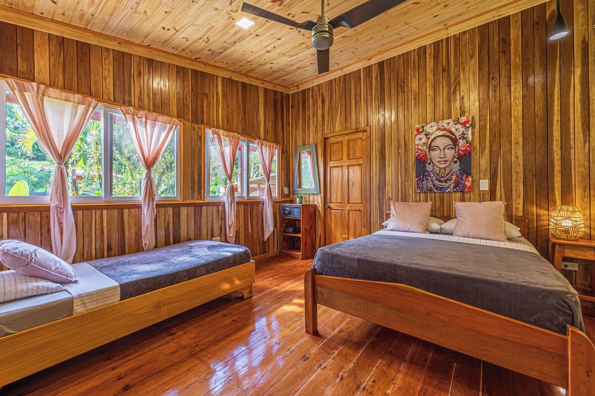 A wooden cabin with two beds, a ceiling fan, and a painting on the wall.