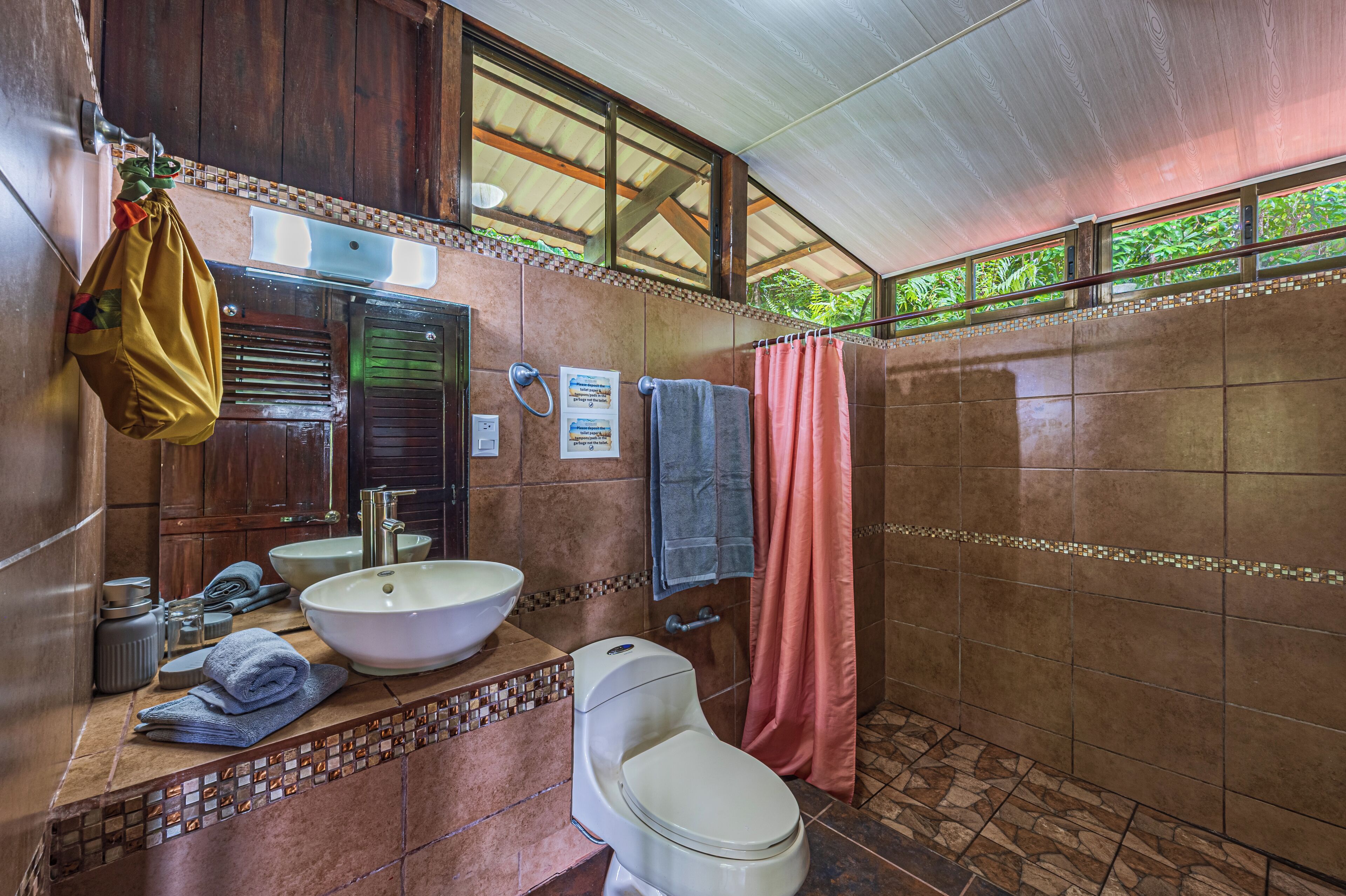 A bathroom with a large sink, toilet, and shower curtain.