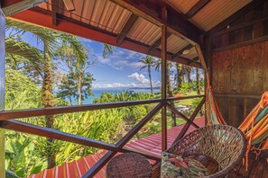 A wooden structure with a view of a tropical landscape, including palm trees and a beach. - Hotel Las Caletas Lodge (Drake Bay)