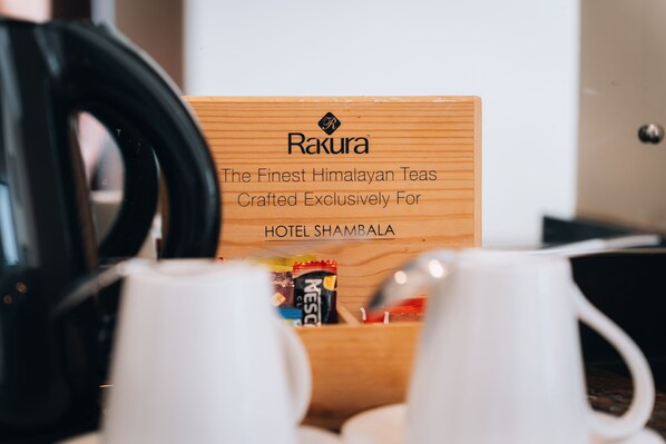 A wooden box with the text "Rakura The Finest Himalayan Teas Crafted Exclusively For HOTEL SHAMBALA" and a coffee maker in the foreground.