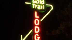 Eine Neonreklame für ‚Gold Trail Lodge‘ mit Pfeilen als Wegweiser.