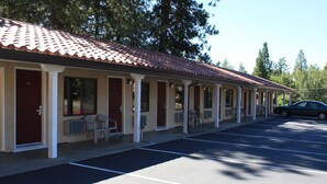 Ein Motel mit Ziegeldach, separaten Zimmern und einem Parkplatz.