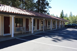 Un motel con techo de tejas, habitaciones individuales y estacionamiento.
