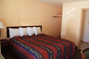 Una habitación de hotel con cama, mesita de noche, lámpara y puerta.