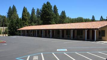 A motel with a tiled roof, a parking lot with marked spaces, and a row of rooms with a covered walkway.