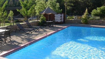 Una piscina al aire libre de temporada, sombrillas