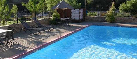 Una piscina al aire libre de temporada, sombrillas