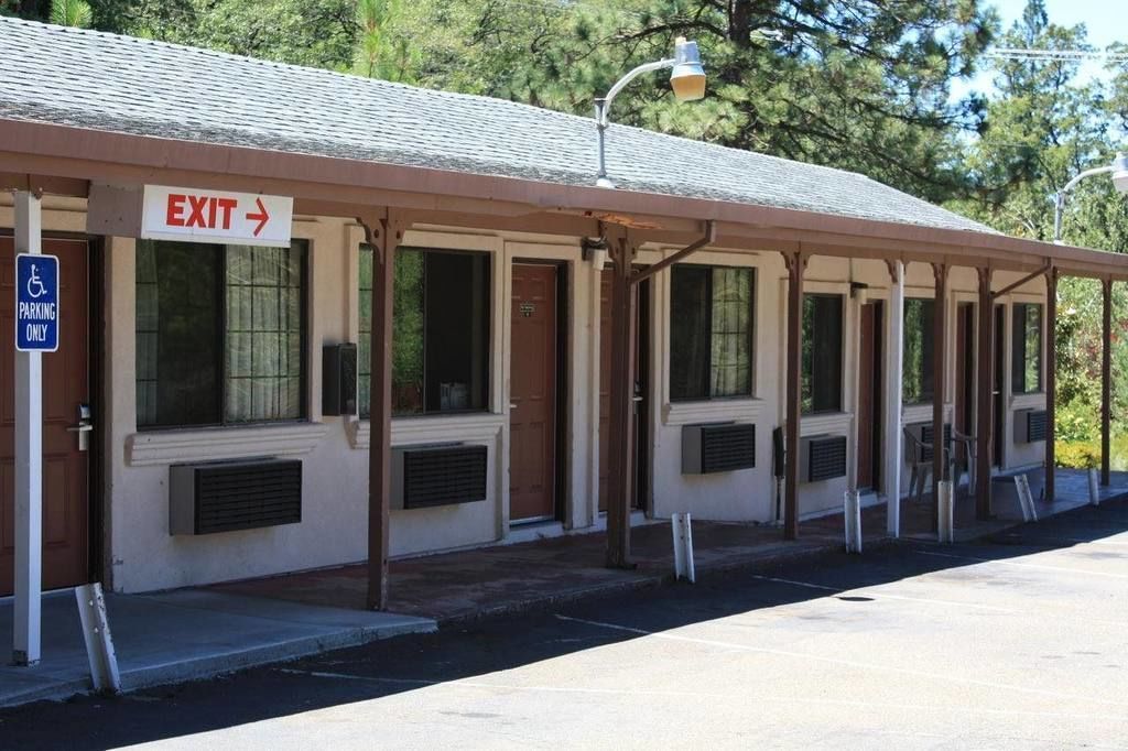 A building with an exit sign, a disabled parking sign, and a covered outdoor area with windows.
