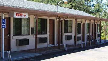 A building with an exit sign, a disabled parking sign, and a covered outdoor area with windows.
