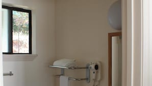 A small bathroom with a toilet, sink, and a hairdryer mounted on the wall. - Mother Lode Motel (Placerville)