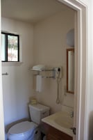 Un baño pequeño con inodoro, lavamanos y secador de pelo montado en la pared.