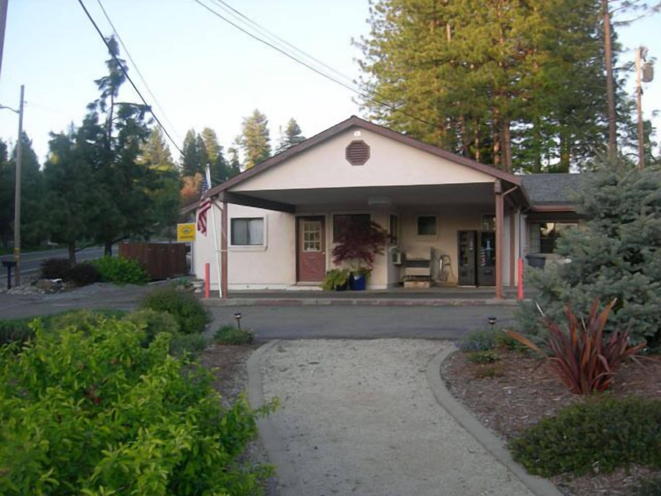 A small, single-story building with a covered porch and a gravel driveway.