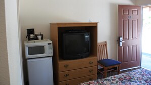 A small room with a wooden cabinet containing a television, a microwave, and a coffee maker. There is a chair and a door with a number sign. - Mother Lode Motel (Placerville)