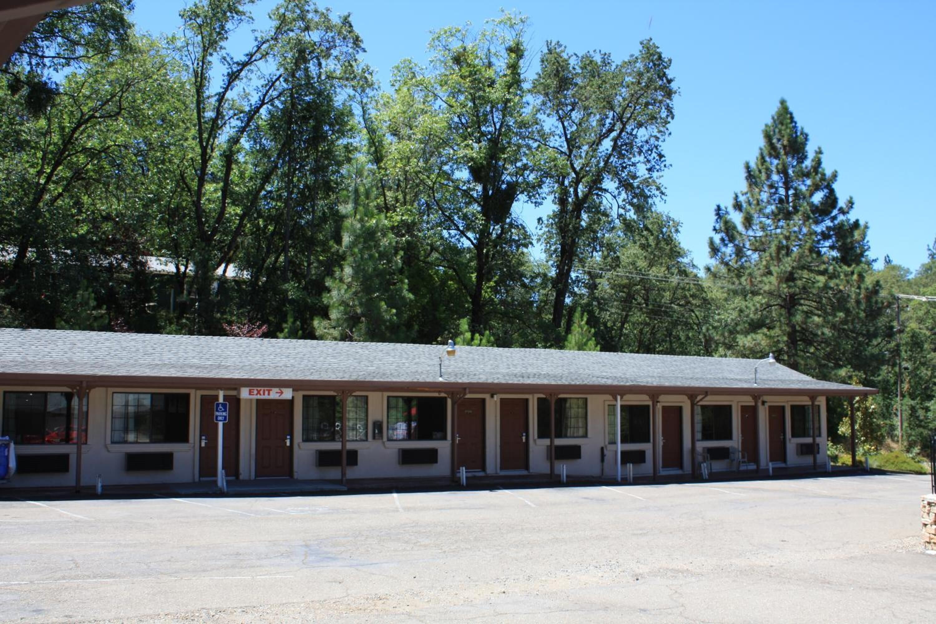 Un motel avec une rangée de chambres, un panneau indiquant la sortie et un parking.