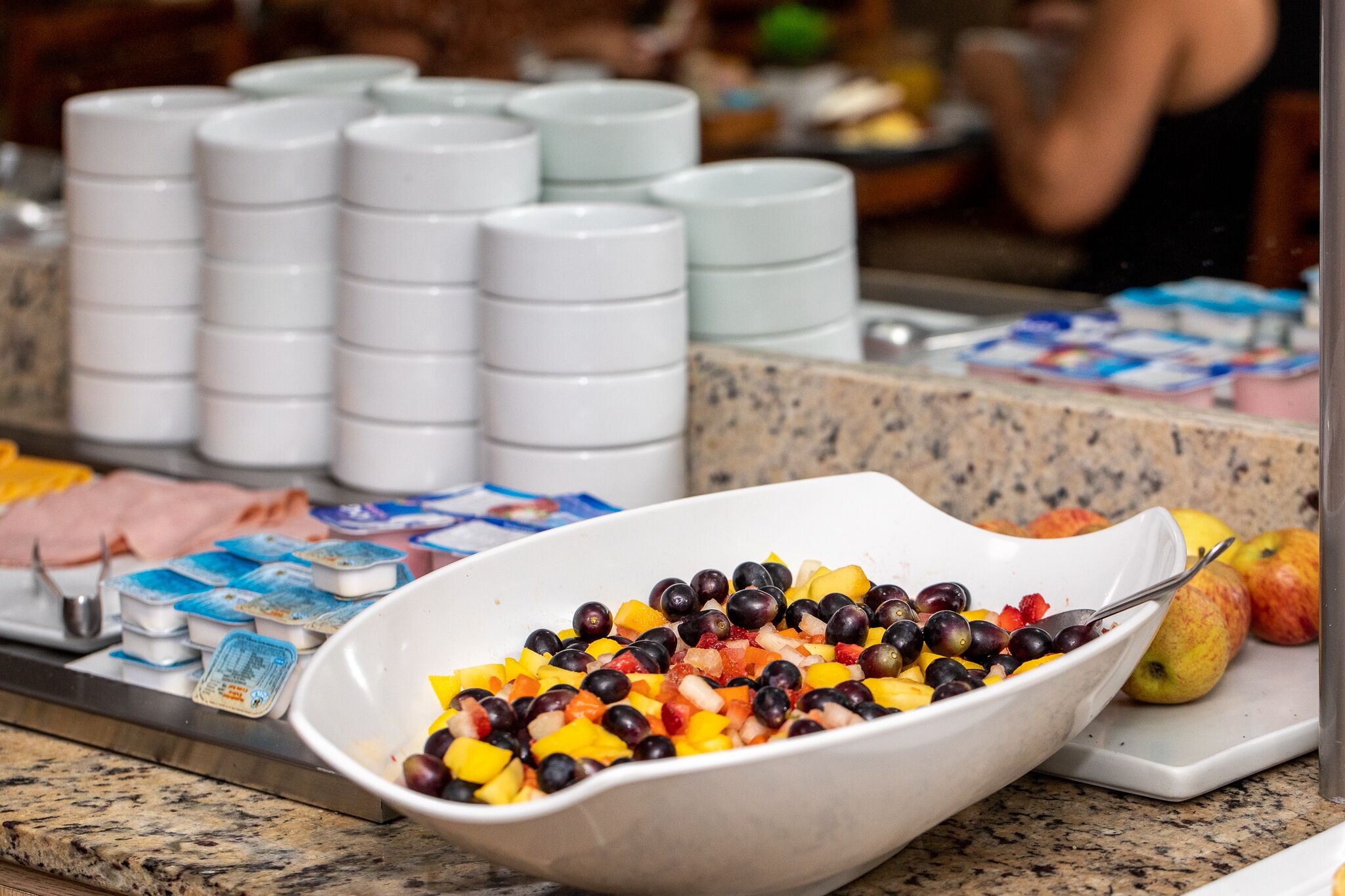 Un bufé con una variedad de alimentos, incluyendo frutas y recipientes de yogur.