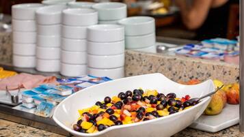 Un bufé con una variedad de alimentos, incluyendo frutas y recipientes de yogur.