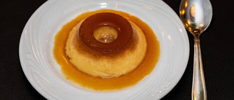 A caramel flan on a white plate with a spoon.