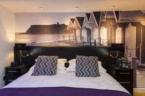 A hotel room with a large bed, two nightstands, a telephone, and a wall-mounted TV. - Mayfield Hotel (Scarborough)