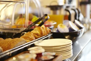 A buffet with various food items including pastries and fruits.