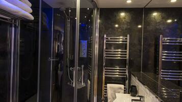 A modern bathroom with a glass-enclosed shower, a white sink, and chrome fixtures.