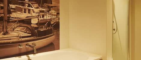 Une salle de bain avec une baignoire, une cabine de douche en verre et un lavabo fixé au mur.