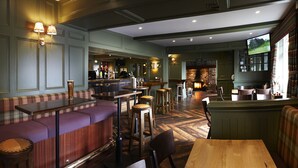 A cozy restaurant with a bar area, wooden furniture, and a fireplace. - Mayfield Hotel (Scarborough)