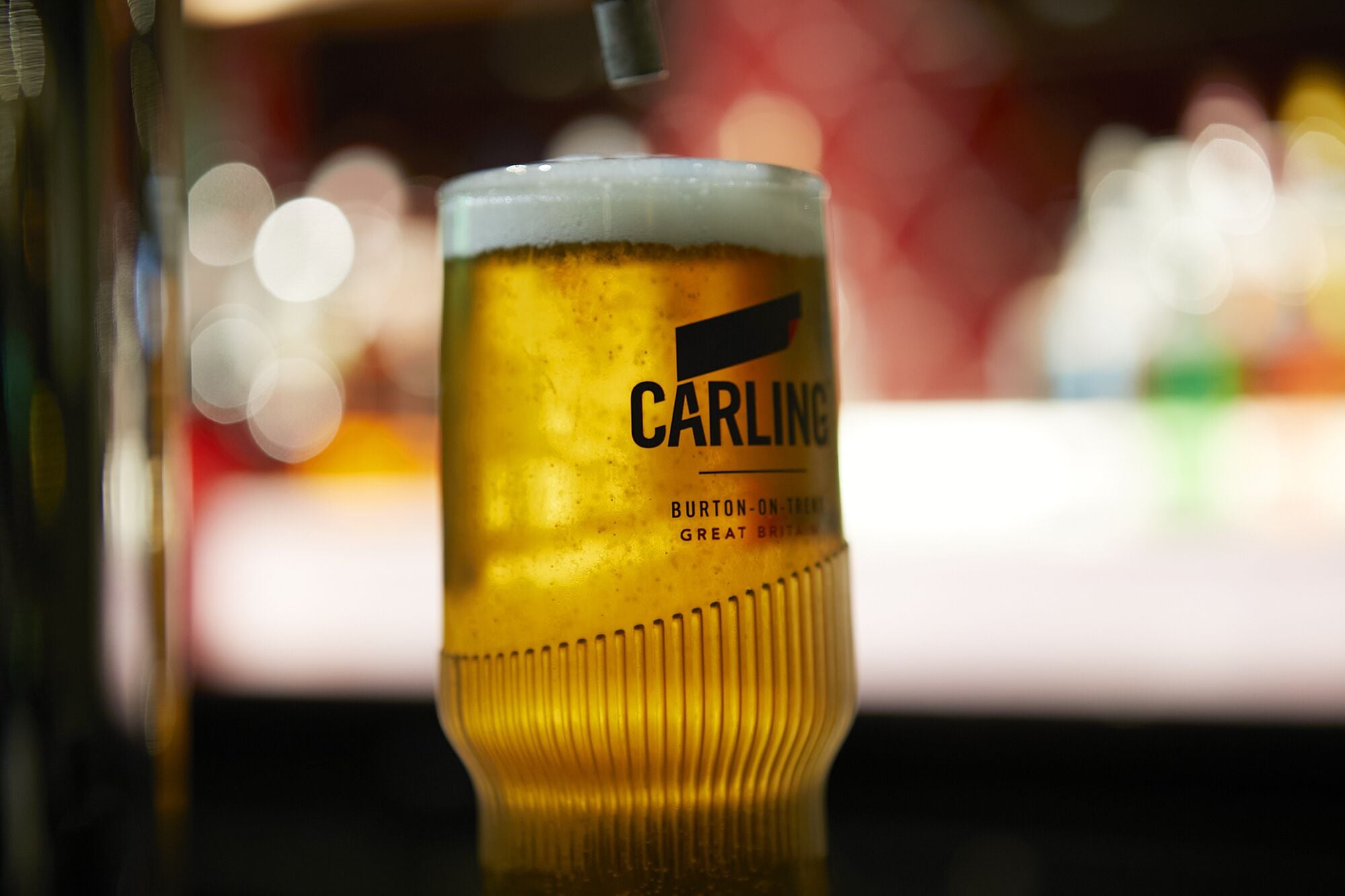 Ett glas öl med en etikett som visar texten: ”CARLING BURTON-ON-TRENT, STORBRITANNIEN”.