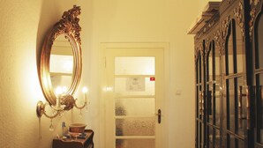 Un pasillo con un espejo, una puerta con paneles de vidrio esmerilado y un armario con puertas de vidrio.
