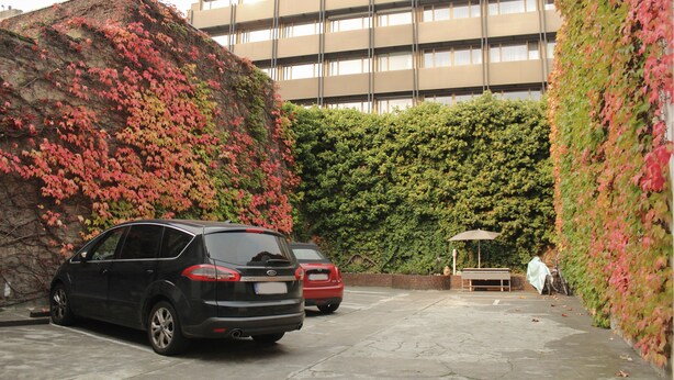Un espacio de estacionamiento con dos autos, un banco y una zona de estar techada.