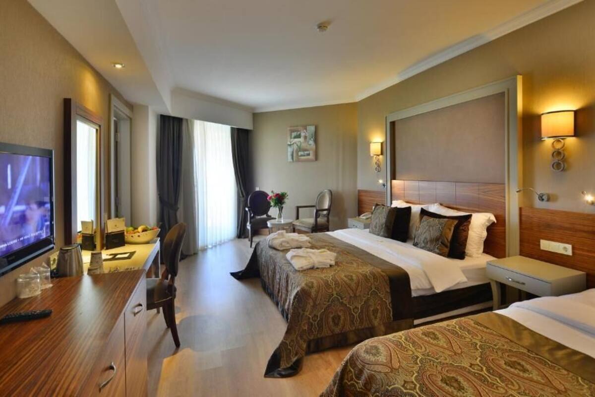 Una habitación de hotel con dos camas, televisión, escritorio y una silla.