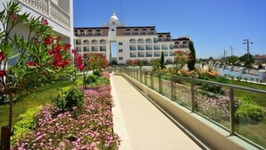 A hotel with a central courtyard, a covered walkway, and a large building with multiple balconies and a dome. - Side Crown Serenity Ultra All Inclusive (Manavgat)