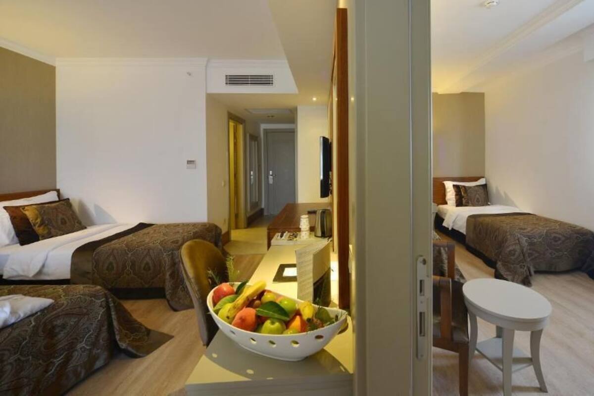 Habitación de hotel con dos camas, una mesa de comedor, un frutero y una mesita auxiliar.