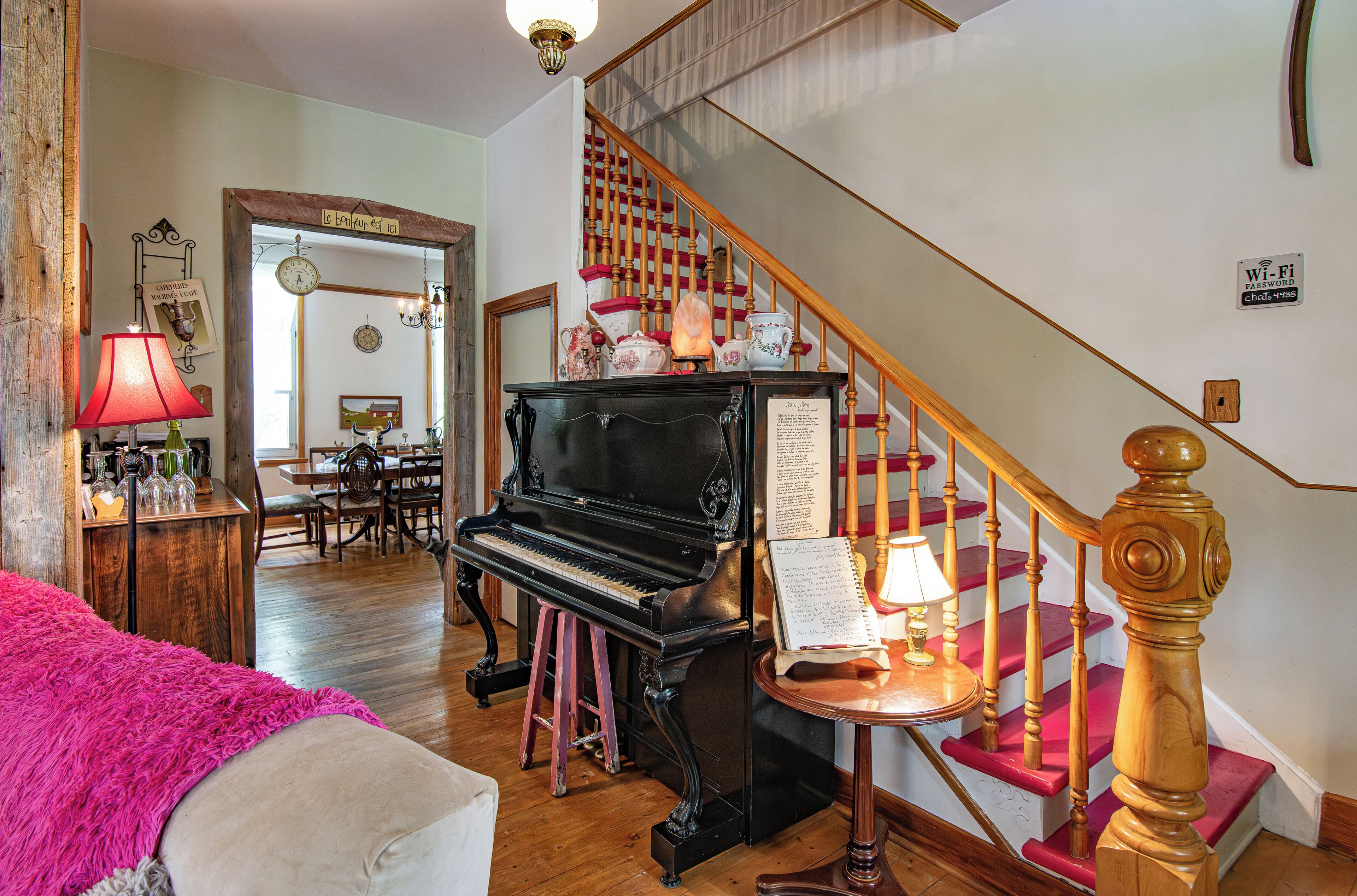A living room with a grand piano, a staircase, and a dining area.