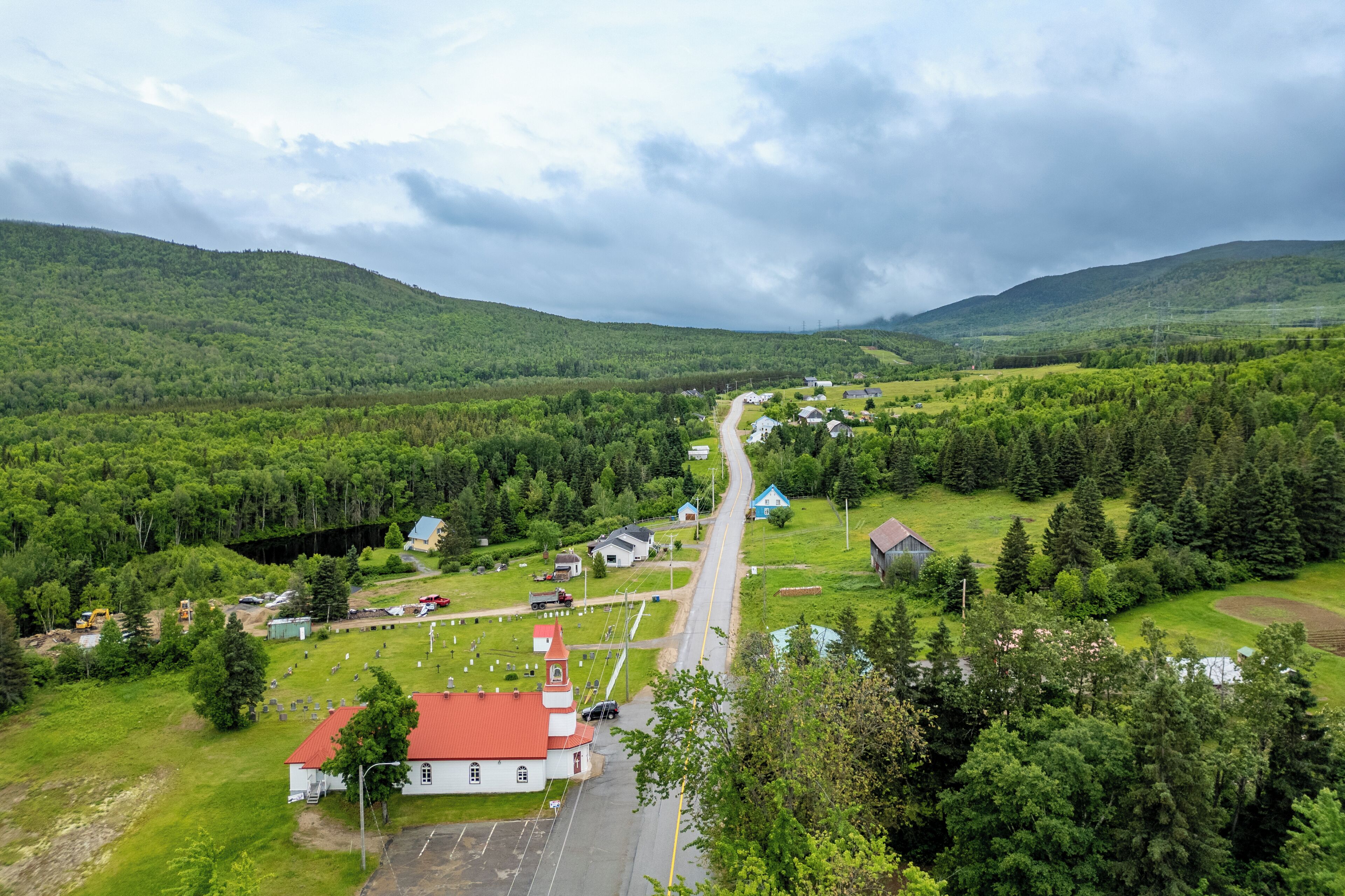 Ländliche Landschaft mit Kirche, Friedhof und verstreuten Häusern.