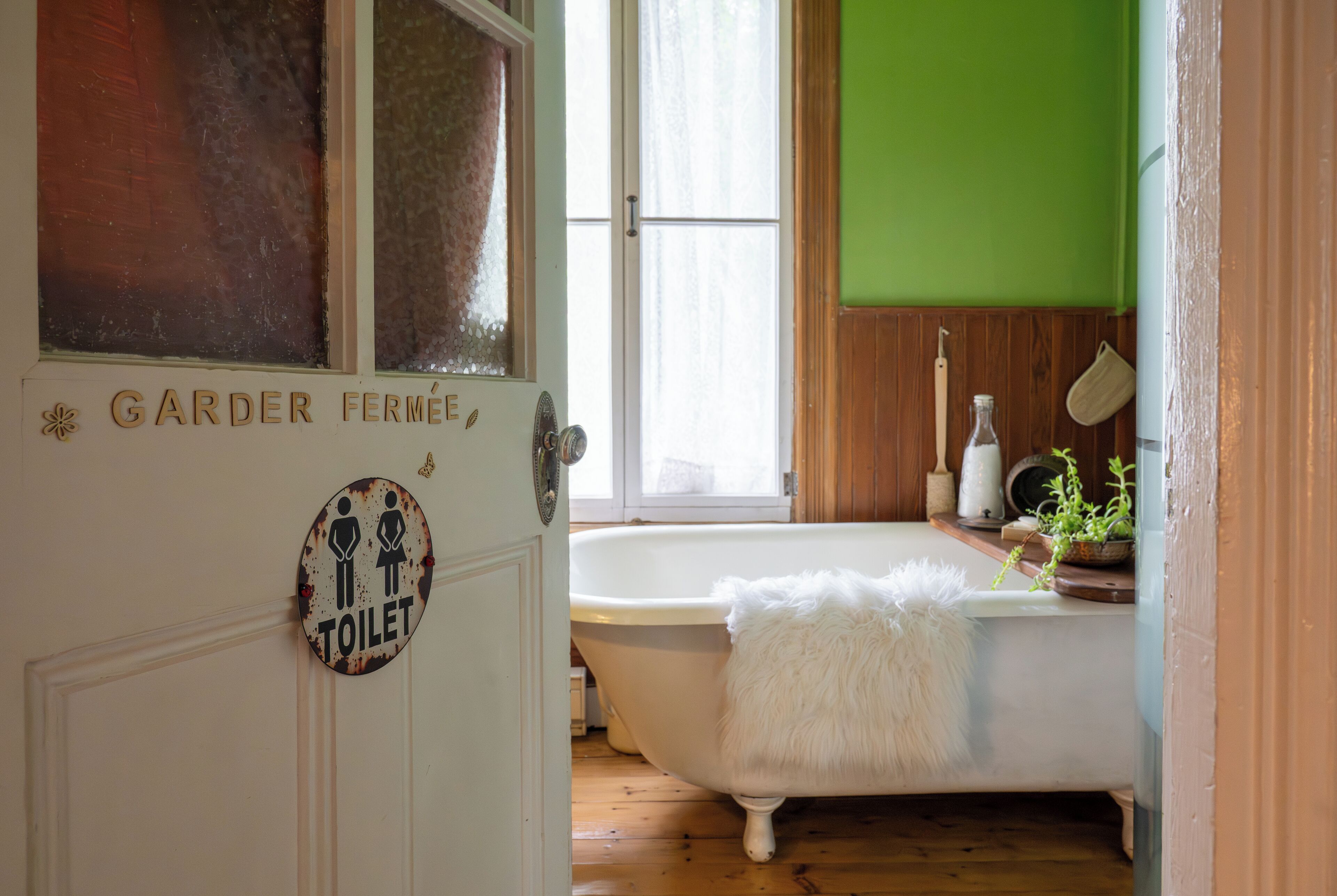 A bathroom with a white bathtub, a white fluffy towel, and a sign indicating a toilet.