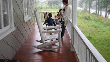 Guests can sit and relax on the porch, taking in the serene views of the surrounding grassy area and trees.