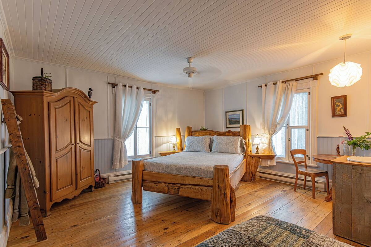 Ein Schlafzimmer mit einem hölzernen Bett, einem Schrank aus Holz, einem Schreibtisch und einem Stuhl.