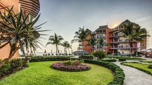 Een resort met een verzorgde tuin, palmbomen en een zwembad.