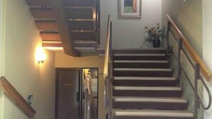 Una escalera con barandas de madera y un accesorio de luz en la pared.