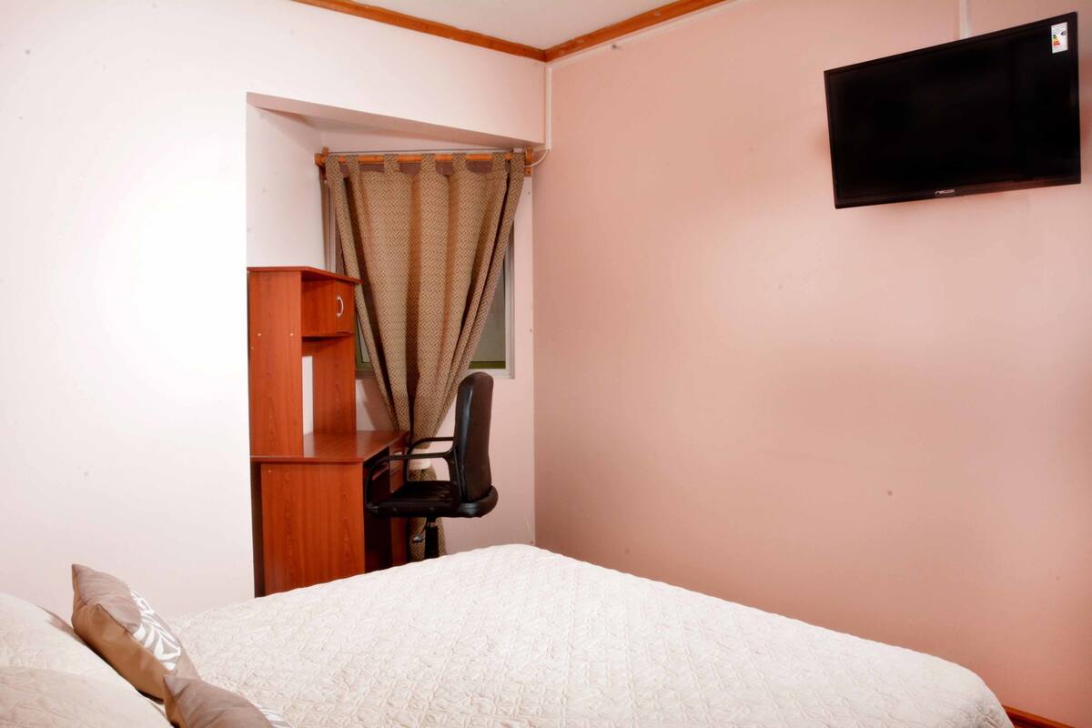 Une chambre à coucher avec un lit, un bureau, une chaise et un téléviseur.
