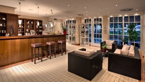 A spacious lobby with a bar area, seating, and large windows offering views. - Suite Hotel Binz Familienhotel Rügen (Binz)