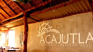 A restaurant interior with a sign reading "ACAJUTLA MARISCOS A LO SALVADORENO". - Las Magnolias Hotel Boutique (San Salvador)