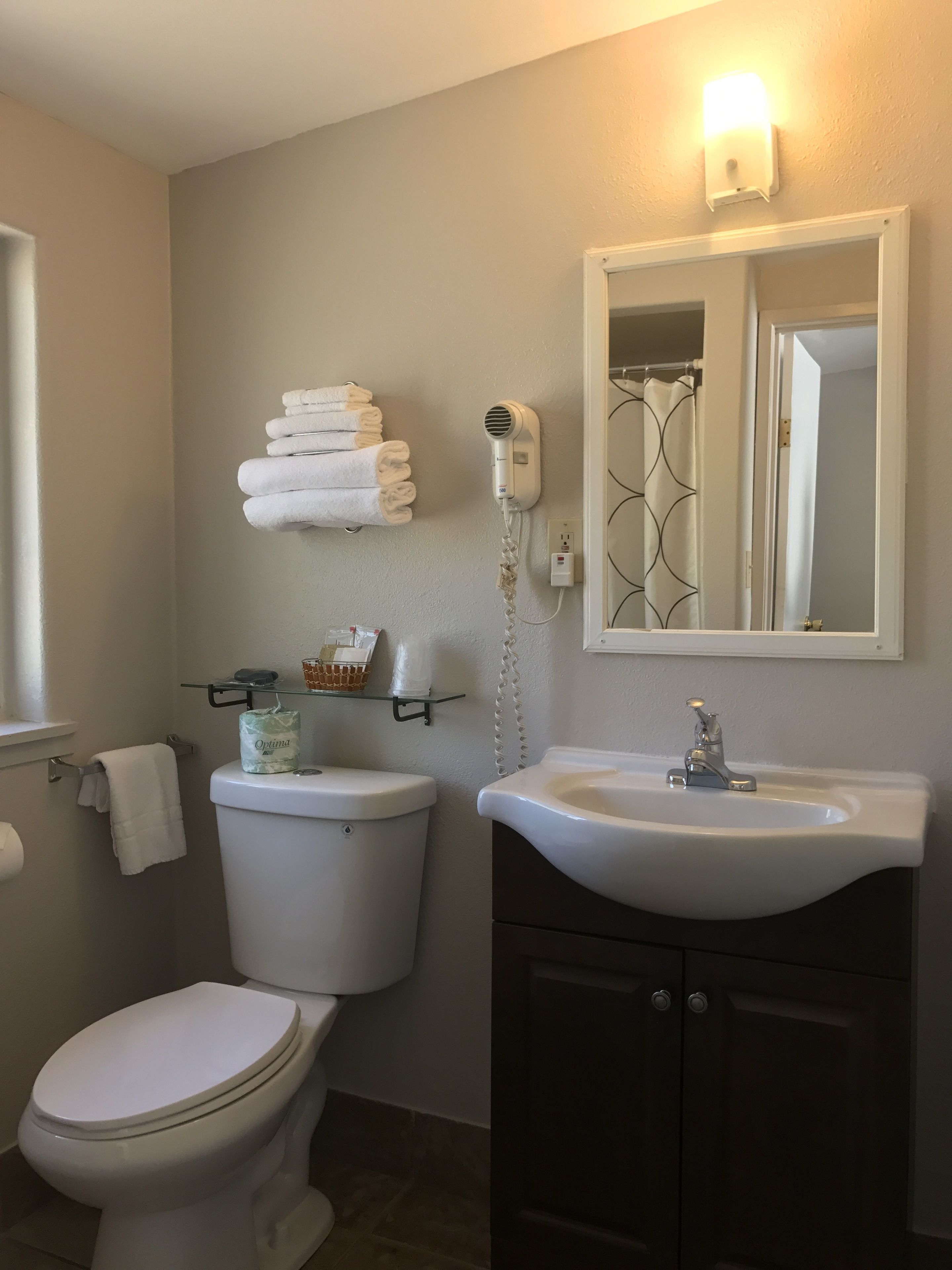 A bathroom with a toilet, a sink, a towel rack, and a hairdryer.