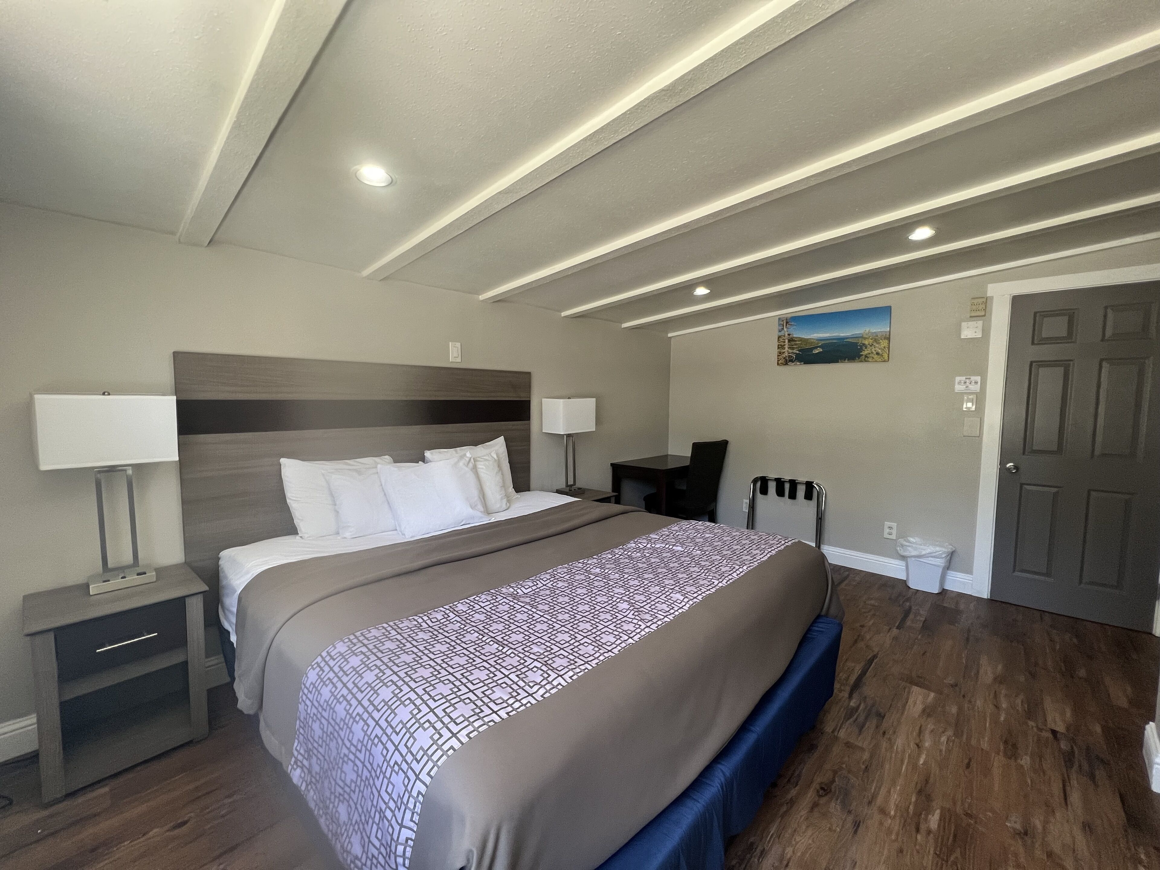 A hotel room with a large bed, bedside tables, a desk, and a chair.