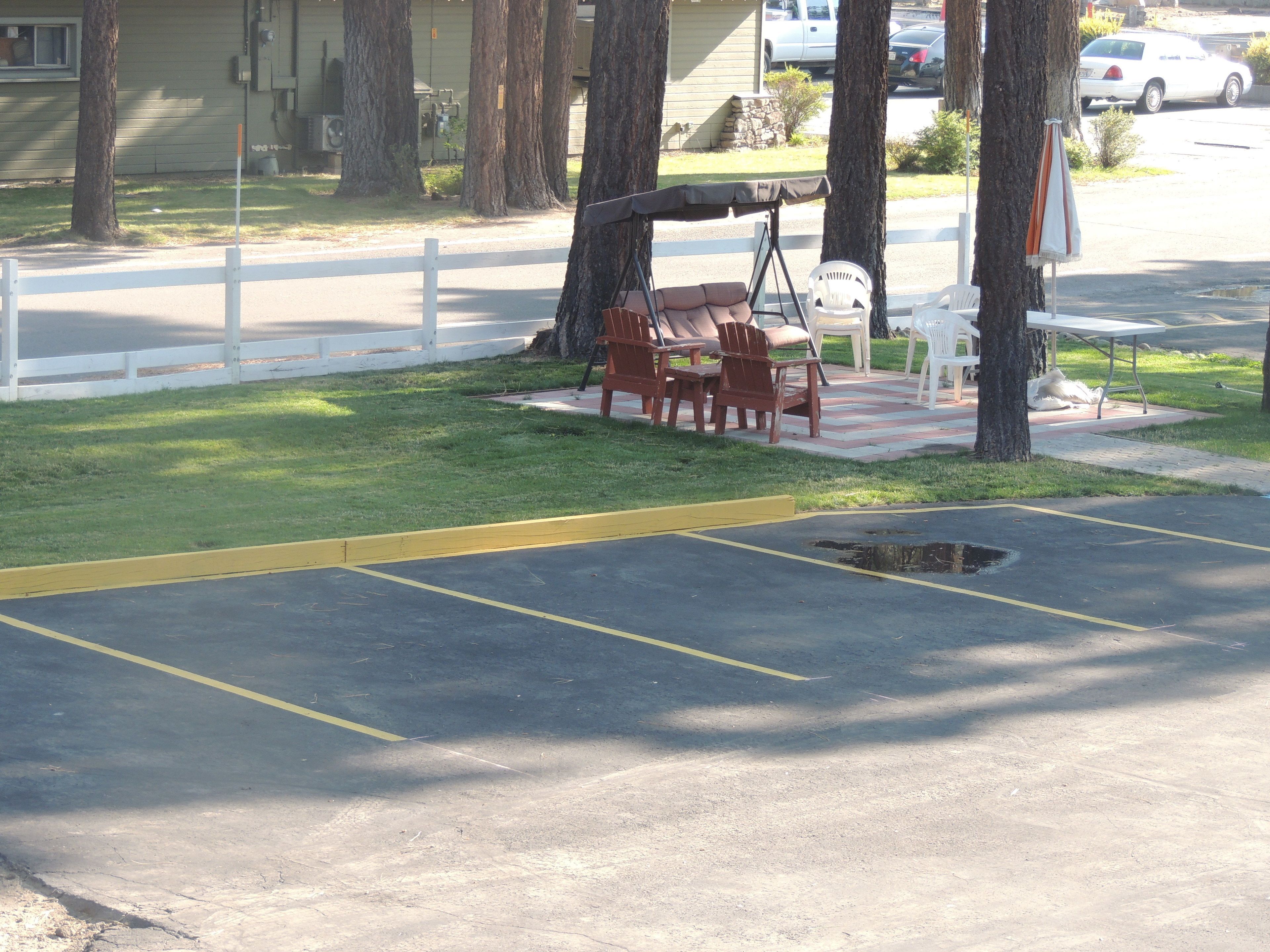 A parking lot with marked spaces, a picnic table with chairs, and a white fence.